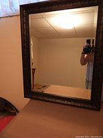 Full front view of the mirror showing the carved wooden frame and beveled glass reflection.