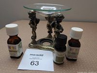 Full lot including brass essential oil holder with glass dish, surrounded by three essential oil bottles: Peppermint, Sage, Magnolia.