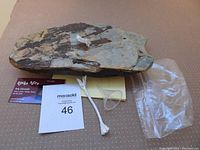 Granite slab with 2 white candle wicks, funnel, instructions, MaxSold lot card, and plastic bag on a beige surface.