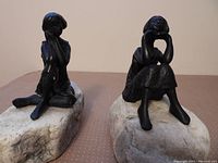 Front view of the two bookends showing the figures of girls sitting on resin rocks.