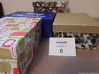 Four Christmas-themed gift boxes of various sizes and designs arranged on a surface