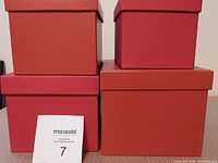 Four red square gift boxes stacked and side by side showing size variation and color texture differences.