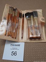 Sheba makeup brushes displayed inside clear plastic slots within cream-colored case, showing different brush types and sizes.