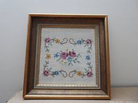 Front view of vintage hand-done needlepoint framed floral artwork showing detail and condition.
