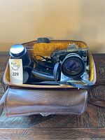 Canon T70 camera with 50mm lens, additional zoom lens, black leather case packed inside brown camera case