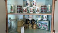 Various ceramic holiday-themed and family photo mugs arranged on upper shelves with large glass storage jars below.