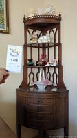 Corner cabinet filled with decorative items including figurines, vases, and small dishes. Image shows the full cabinet and its upper and lower storage areas.