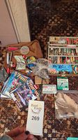 Full overhead photo showing fishing gear assortment including fishing knives, hooks, flies, weights, bobbers, reel, fishing line spools, magazines, and other accessories on carpet