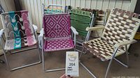 Seven vintage folding lawn chairs arranged outdoors, showing various colors and woven webbing patterns.