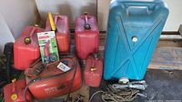 Multiple red plastic fuel tanks and jerry cans, Bosch red fuel tank with gauge and hose, large blue Tote-Along water tank, two metal anchors with rope.