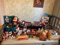Wide shot of various holiday decorations laid out including plush toys, mugs, wreaths, figurines, and ornaments.