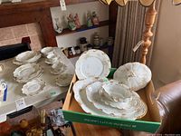 Wide view of Limoges Théodore china pieces including plates and teacups arranged on table and in box.