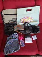 Nine assorted purses, bags, wallets and pouches displayed on a red sofa.