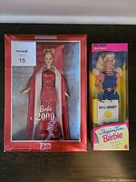 Two Barbie dolls in original packaging displayed side by side on the floor, Barbie 2000 on left in red box, Walmart Shopping Time Barbie on right in pink box.