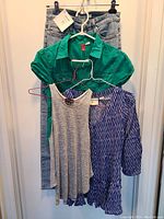 Four clothing items on hangers: light blue jeans, green short-sleeve button-up shirt, gray sleeveless top, and blue patterned blouse.