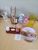 Top-down view of all items showing glass candle holders, the vases, and yellow square vase, blue and white porcelain vase, pink beads vase, plate, small boxes, and coasters.