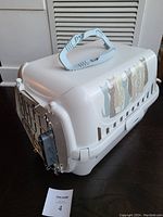 Side view of assembled white plastic pet carrier with top handle and decorative cats decal