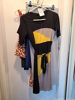 Colorblock BCBG dress with black, yellow and beige panels hanging on hangers with other clothing