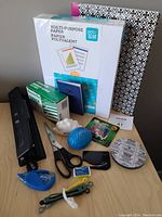 Overview of office supplies showing paper packs, hole punch, scissors, and other items.