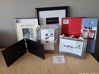 Lot of nine picture frames of varying styles and sizes arranged on table showing variety and original packaging for some.