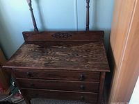 Front view of the antique wooden dresser showing two drawers, decorative carved backboard, and wear on surface.
