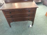 Full view of antique wooden dresser showing three drawers and raised back strip