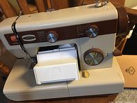 Vintage Eaton Viking Con II sewing machine front view showing control dials, stitch selector, and built-in light on beige and brown body.