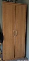 Closed laminate wardrobe cabinet showing wood finish and handles.