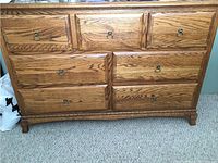 Front view of solid wood long dresser with six drawers, visible wood grain, and metal ring handles.