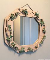 Front view of the sculpted ivy ceramic frame mirror hanging on a wall showing detailed ivy leaves design