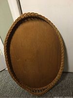 Front view of the oval wicker cane serving tray showing the wooden base and braided wicker border.