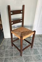 Front and side view photo of wooden chair with woven wicker grass seat showing chair design and condition.