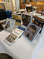 Photo showing all eight art and design coffee table books arranged on a table in a living space, showcasing front covers with a variety of themes including Fabergé, Vatican, London Churches, Islamic art, Art Deco, and others.