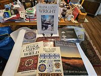 Photo featuring all 7 art and design themed books arranged on a white cloth with a cluttered background including a coffee cup, various boxes and papers.