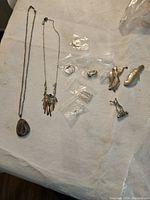 All 11 costume jewelry pieces laid out on a white cloth with two necklaces and various brooches and rings visible.