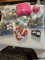 Overview of 25 assorted balls of yarn in various colors and packaging on white surface.