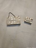 Photo showing both items lying flat, mother of pearl checkerboard pattern visible