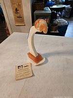 Full front and side view of the alabaster Olympic diver statue on a table with a paper certificate nearby.