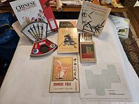 Top-down photo showing all books and Chinese brush painting art supplies including a palette and brushes arranged on a white surface.