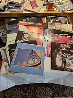 Photo showing multiple rock vinyl record album covers fanned out on a table; includes artists such as Dire Straits, Kim Mitchell, Van Halen, and John Cougar Mellencamp.