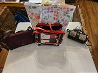 Overview photo showing all four handbags arranged on a white cloth on table