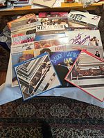 Photo showing a collection of vinyl record covers laid out on a table, featuring artists such as Barry Manilow, The Beatles, Men at Work, and others.