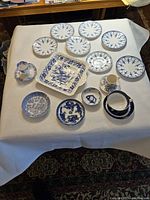 All 17 pieces arranged on white cloth showing variety in size and patterns primarily blue floral on white china.