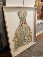 Full view of framed collage artwork leaning against wall