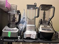 Group shot of all three appliances on shelf: Ninja food processor at left, Breville blender center, Ninja 1500W blender right