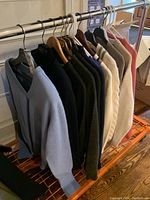 Overview of twelve men’s sweaters hanging on a rack