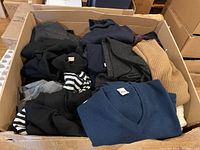 Cardboard box containing folded men's sweaters in various colors and styles