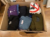 Overview of nine folded men’s tops in a cardboard box