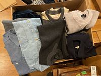 Top-down view of assorted folded men’s shirts and sweaters in box