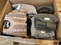 Six folded sweaters in cardboard box